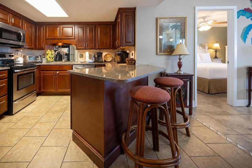 Rich wood cabinetry complements the modern kitchen with a breakfast bar and seating, leading to the master suite