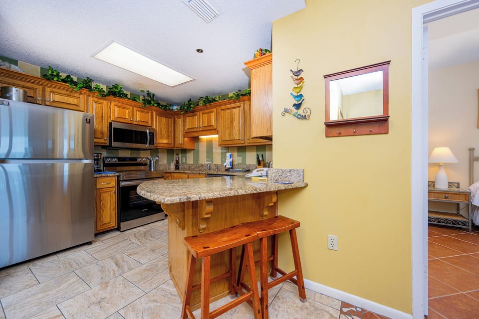 Prepare meals in the inviting kitchen, featuring wood cabinetry, granite counters, and stainless appliances