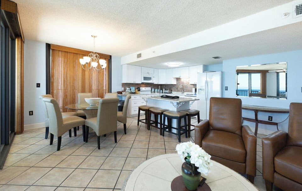 The fully-equipped kitchen features rich wood cabinetry, a breakfast bar with seating, and a stylish stone backsplash