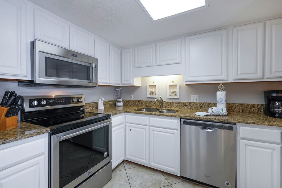 Kitchen features white cabinetry, granite countertops, and stainless appliances, creating a bright and functional space