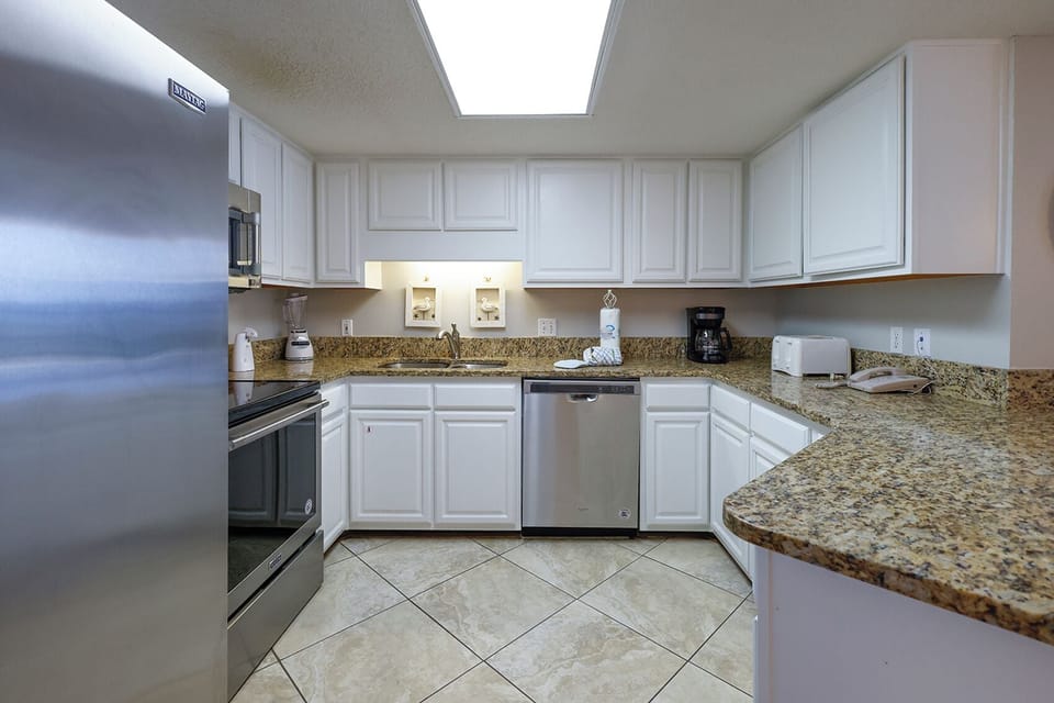 Modern kitchen featuring white cabinetry, granite countertops, and stainless appliances, perfect for meal preparation