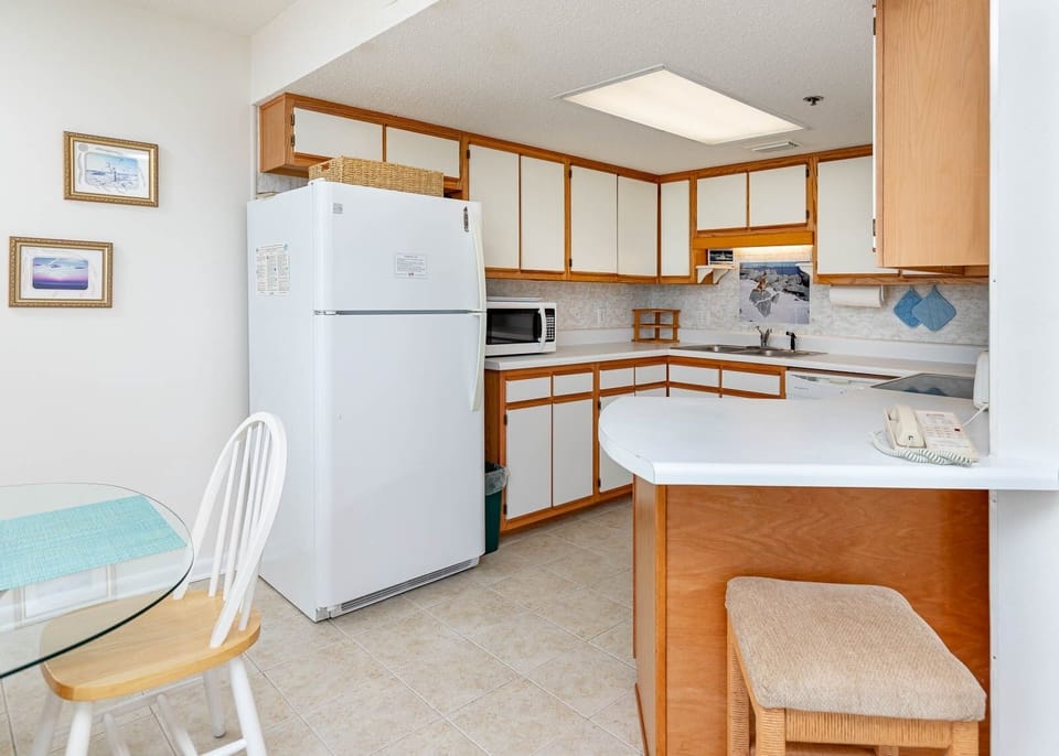 Prepare meals in this kitchen featuring white appliances and a cozy dining area with a glass table