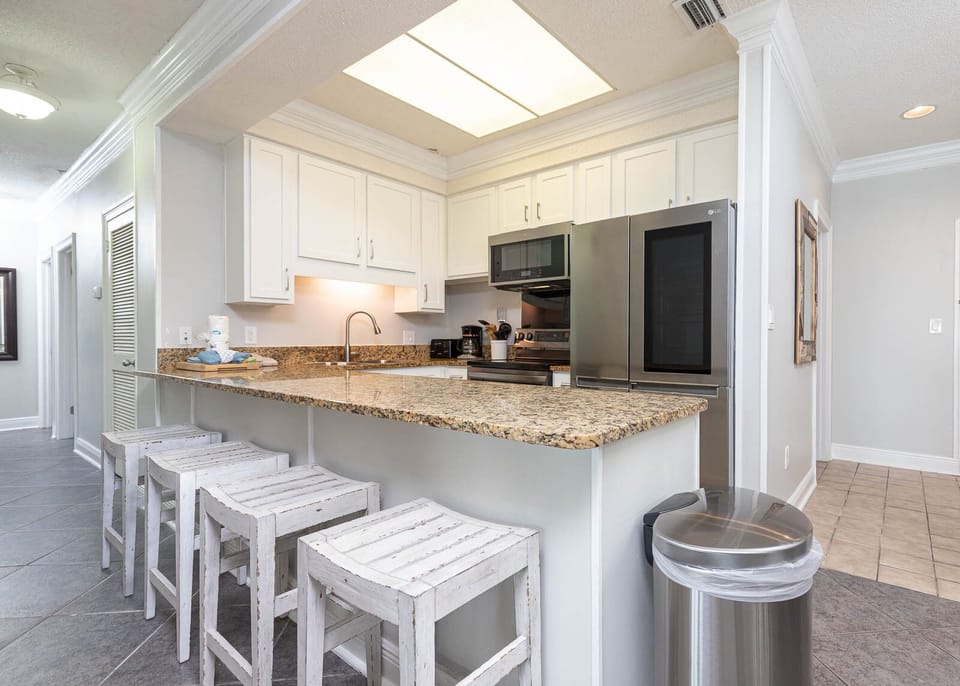This kitchen features modern stainless appliances, granite countertops, and a breakfast bar with stools for casual dining