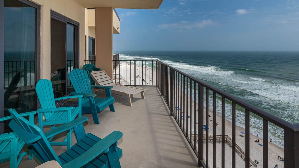 Relax on the balcony's colorful chairs while enjoying breathtaking views of the sandy beach and rolling waves