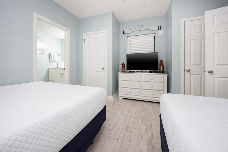 Enjoy restful nights in this relaxing guest room with two double beds, a TV, and soft blue walls that create a calming vibe