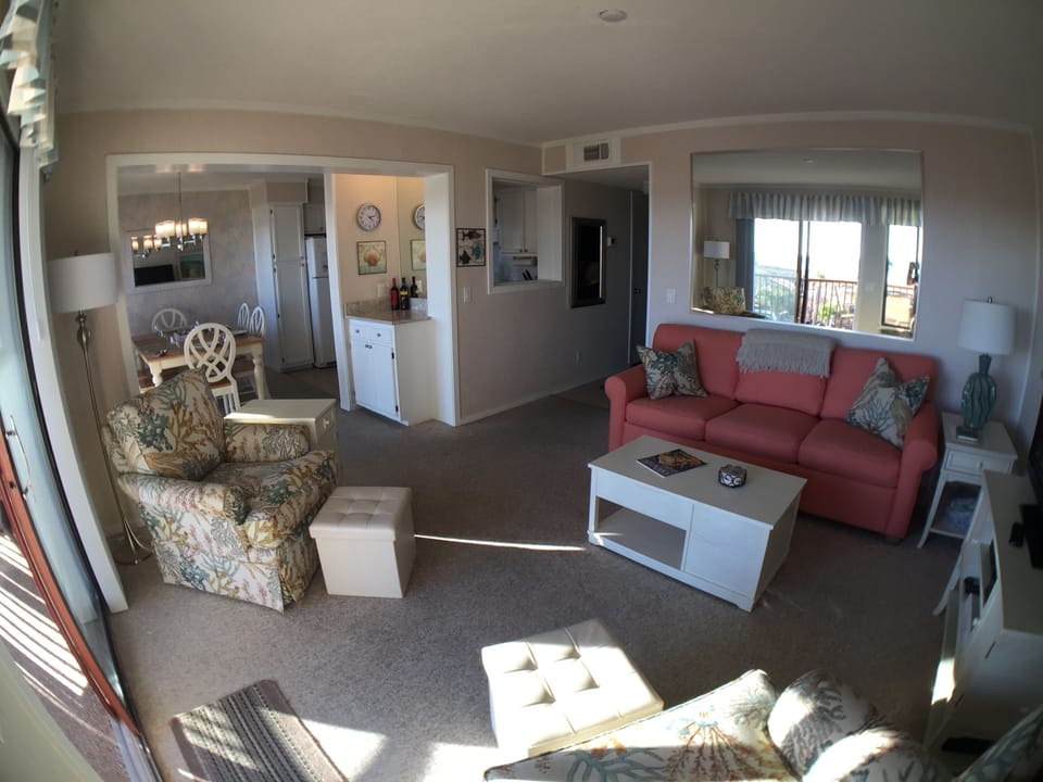 Wide angle view of the living room, dining room, large reflective mirror.
