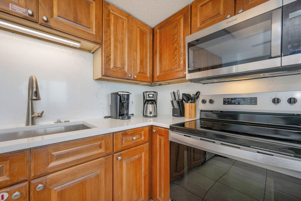 Steam rises from the coffee maker as you prepare morning drinks in the cozy kitchen nook with warm wood cabinets
