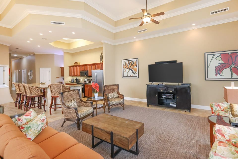 This cozy living area features a large TV, comfortable seating, and a view of the modern kitchen with rich wood cabinetry