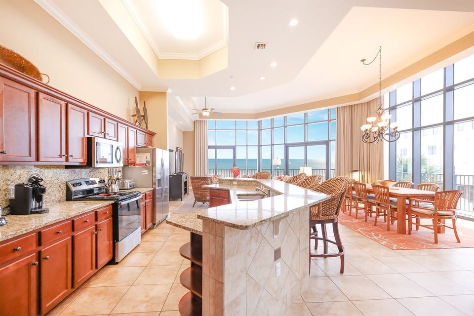 This kitchen features rich wood cabinetry, stainless appliances, and a stunning beachfront view through large windows