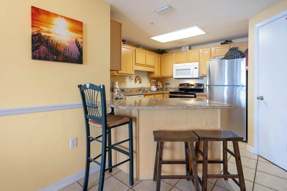 Enjoy cooking and dining at the spacious kitchen bar, complemented by warm tones and a vibrant sunset artwork
