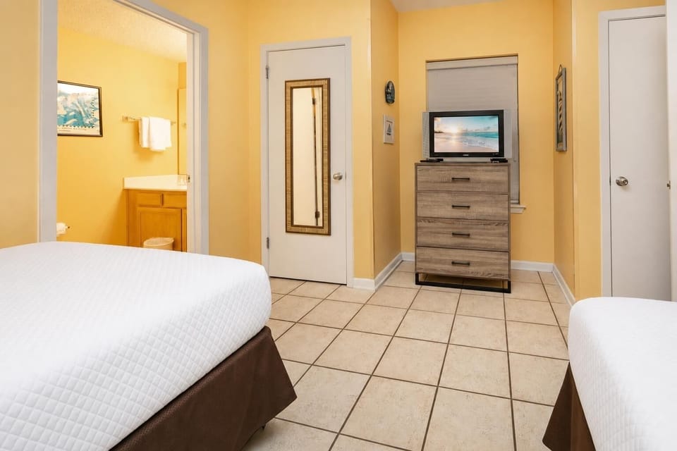 Relax in this cheerful guest room with double beds, a TV, and a bright atmosphere enhanced by sunny yellow walls