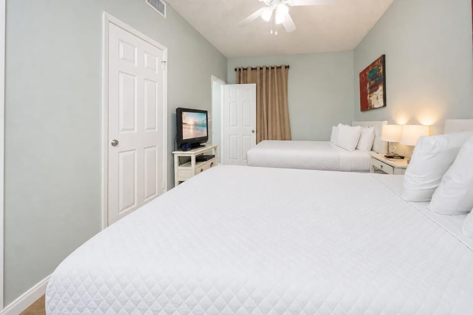 Relax in this comfortable guest room featuring two beds, a TV, and soft lighting for a restful stay