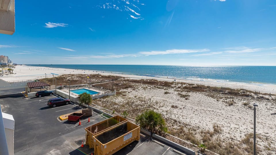 This bright view showcases a beach front with soft white sands and a sparkling pool, perfect for relaxing vacations