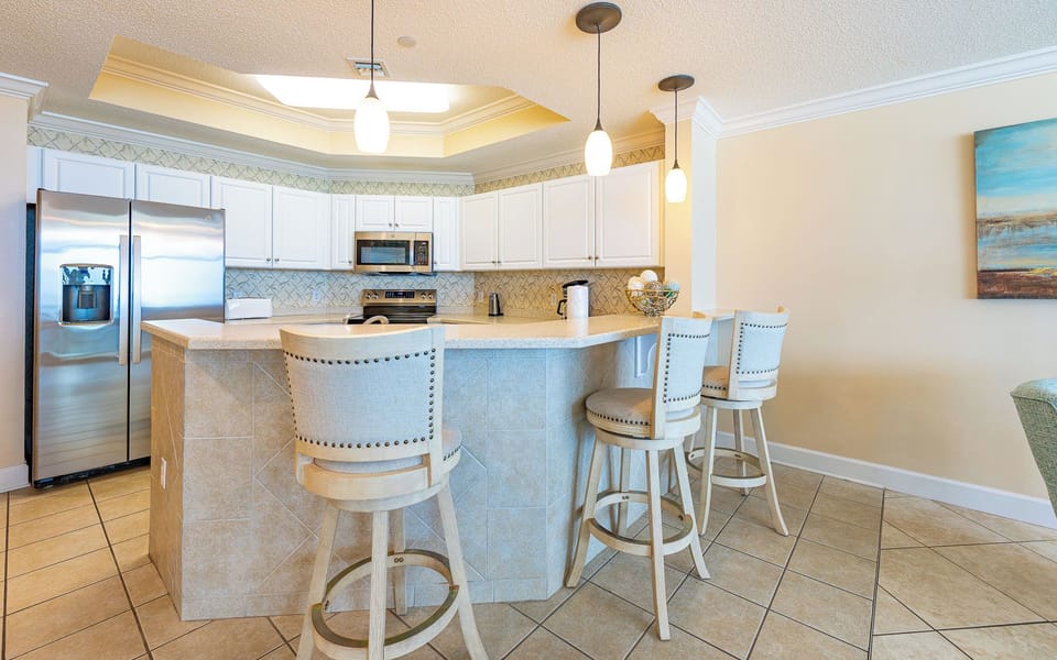 Soft pendant lights hover over the breakfast bar where you sip morning coffee and plan your day by the coast