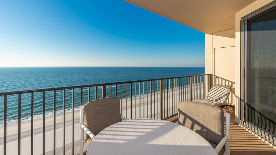 Bask in the sun on the balcony with a table and chairs, enjoying expansive views of the tranquil beach below