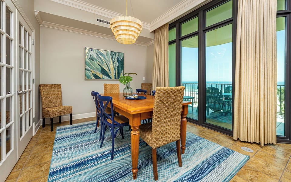 Gather around the wooden table in the dining room as sunlight filters through glass doors onto the balcony