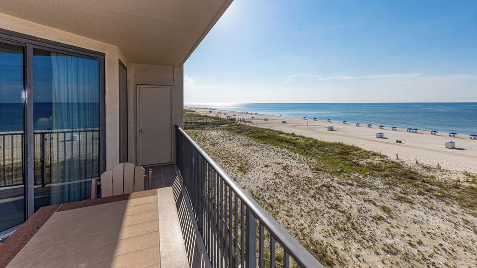Your balcony lets you watch families play and umbrellas dot the white beach under a clear blue sky