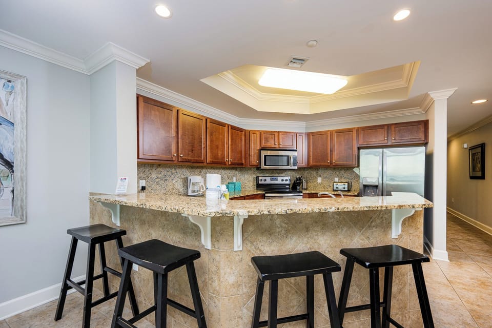 This kitchen features rich wood cabinetry, stainless appliances, and a spacious granite countertop perfect for casual dining