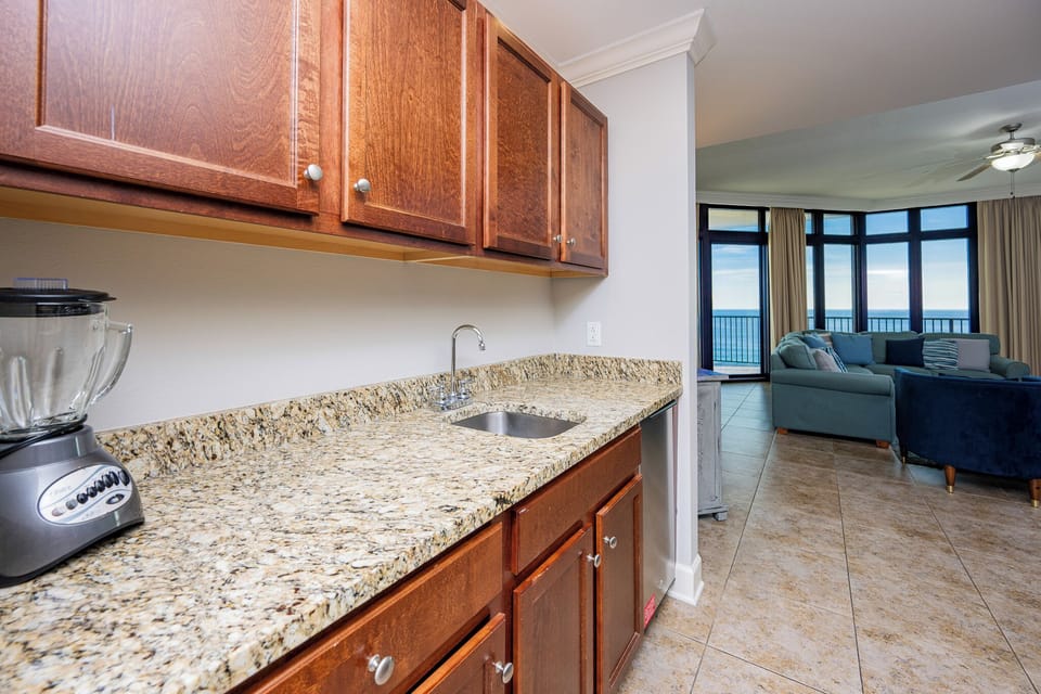 The wet bar area features rich wood cabinetry, a blender, and granite countertop for entertaining guests and refreshments