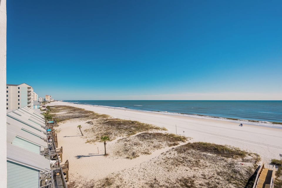 This stunning view showcases a beautiful beachfront with soft white sand and gentle waves, perfect for relaxation