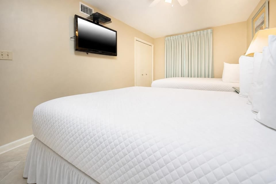 Relax in this inviting guest bedroom featuring two comfortable double beds and a TV during your stay