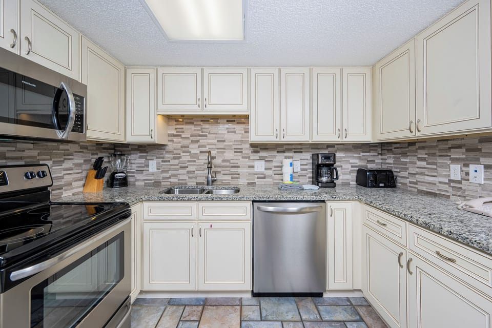 Light cabinetry, granite countertops, and a stylish backsplash complete this kitchen, creating a welcoming cooking space