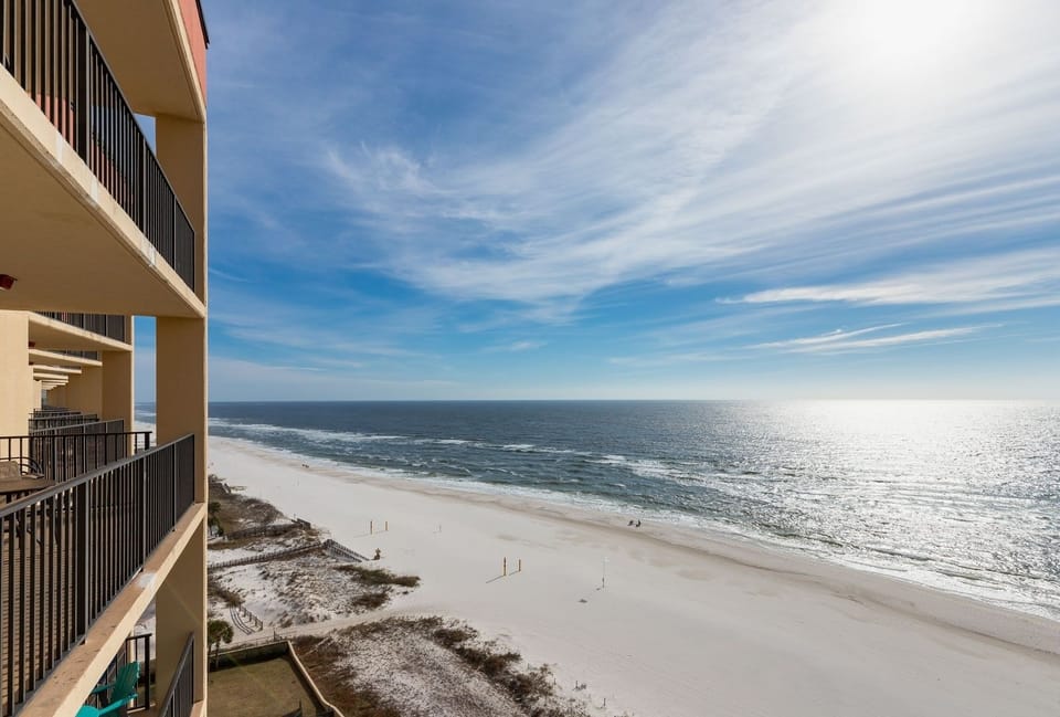 Enjoy a serene view of the expansive beach with soft white sand and gentle waves from the balcony