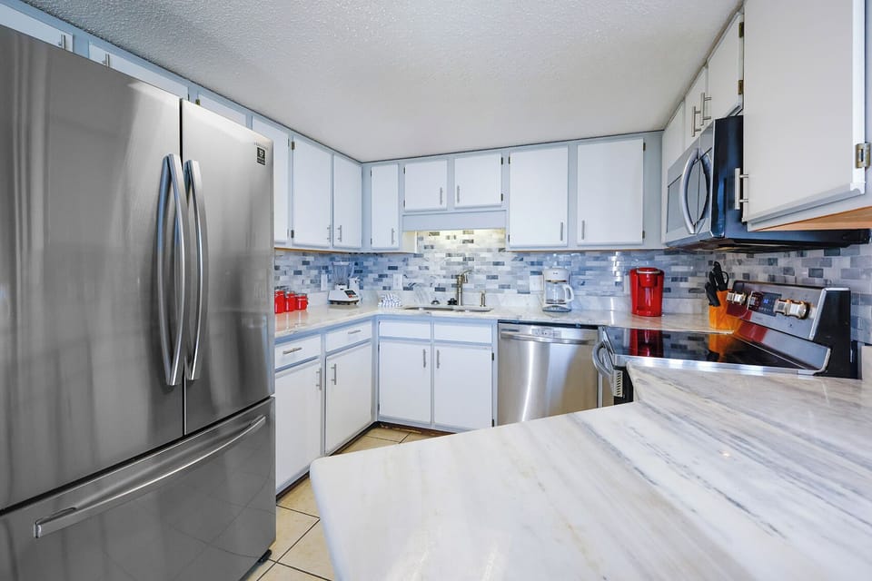 The modern kitchen features sleek cabinetry, a marbled countertop, and a stylish backsplash, perfect for culinary adventures