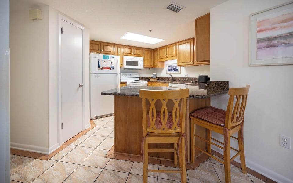 Wooden cabinetry complements the granite countertops in this inviting kitchen area with a breakfast bar and seating