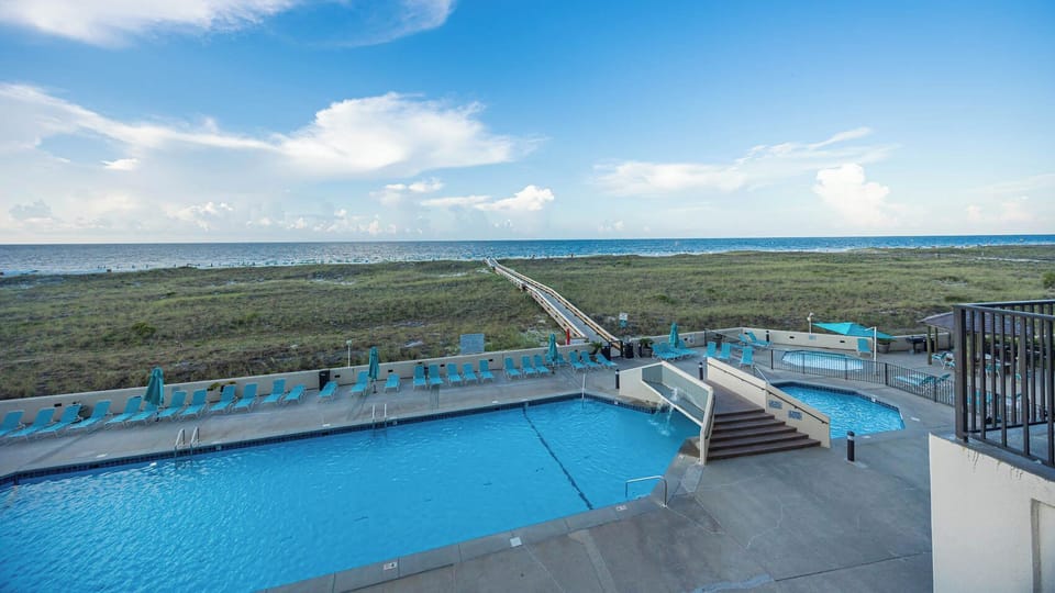 Inviting pool area with a kiddie pool, lounge chairs, and a scenic path leading to the beach, perfect for relaxation and fun