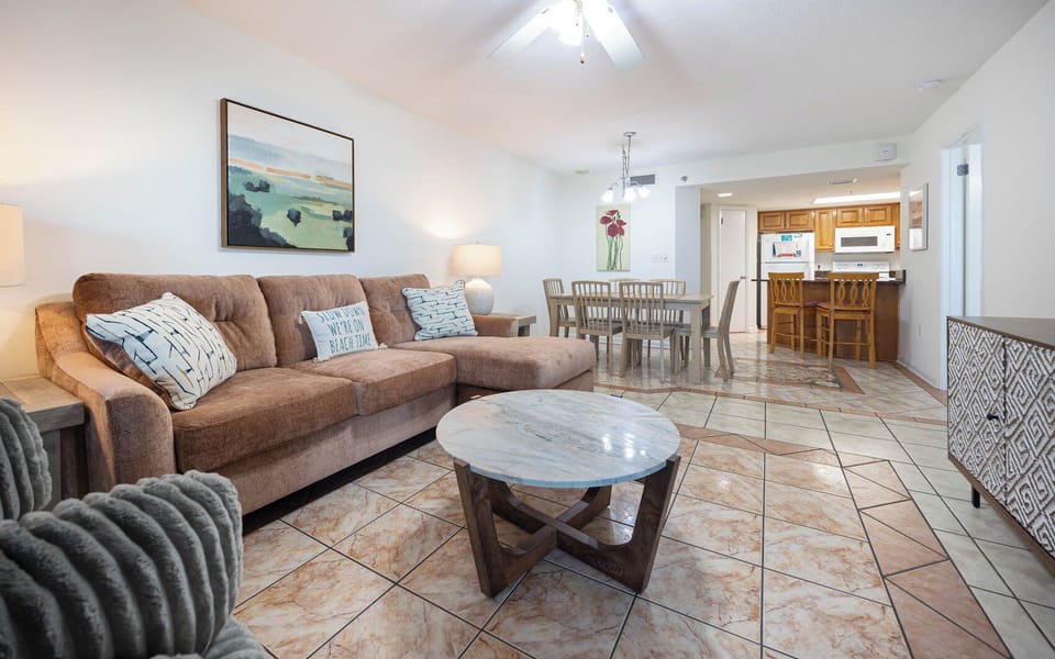 Cozy living area features a plush sofa with queen sleeper, a stylish coffee table, and a dining space in the background