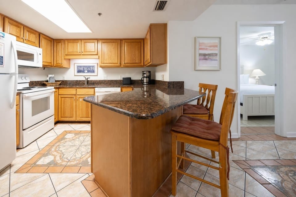 Warm wood cabinetry complements the granite countertops in this inviting kitchen, featuring a breakfast bar with seating
