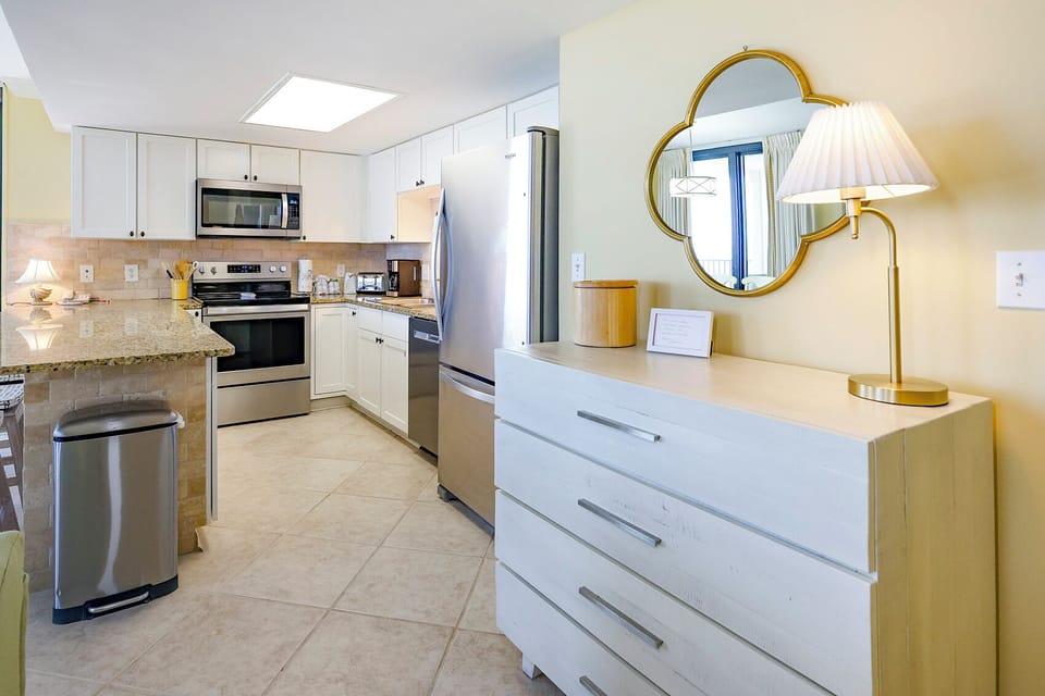 Stylish kitchen features granite countertops, white cabinetry, and a convenient breakfast bar with seating