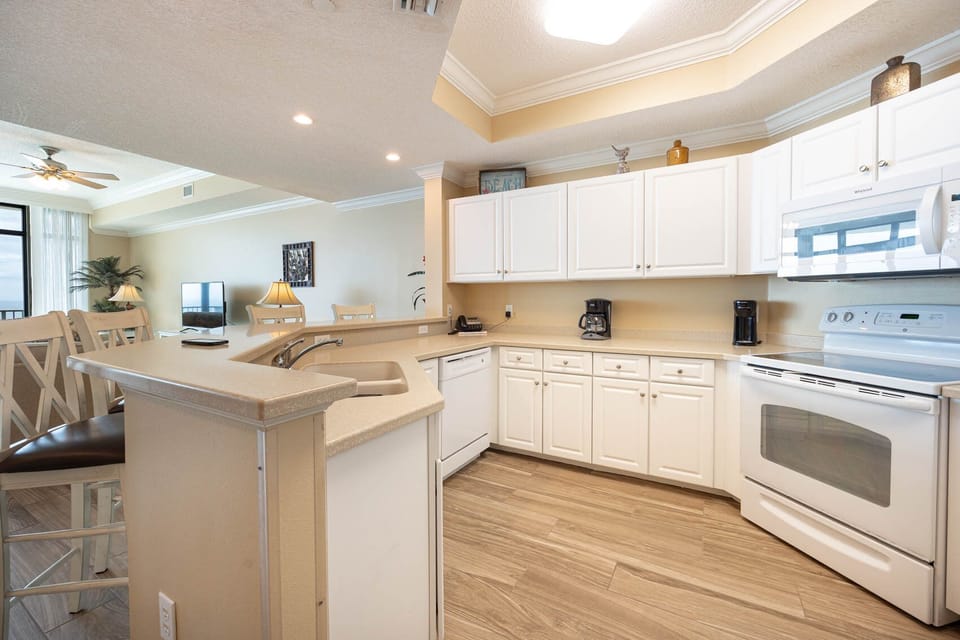 Prepare meals in this kitchen with sleek cabinetry, white appliances, and spacious countertops