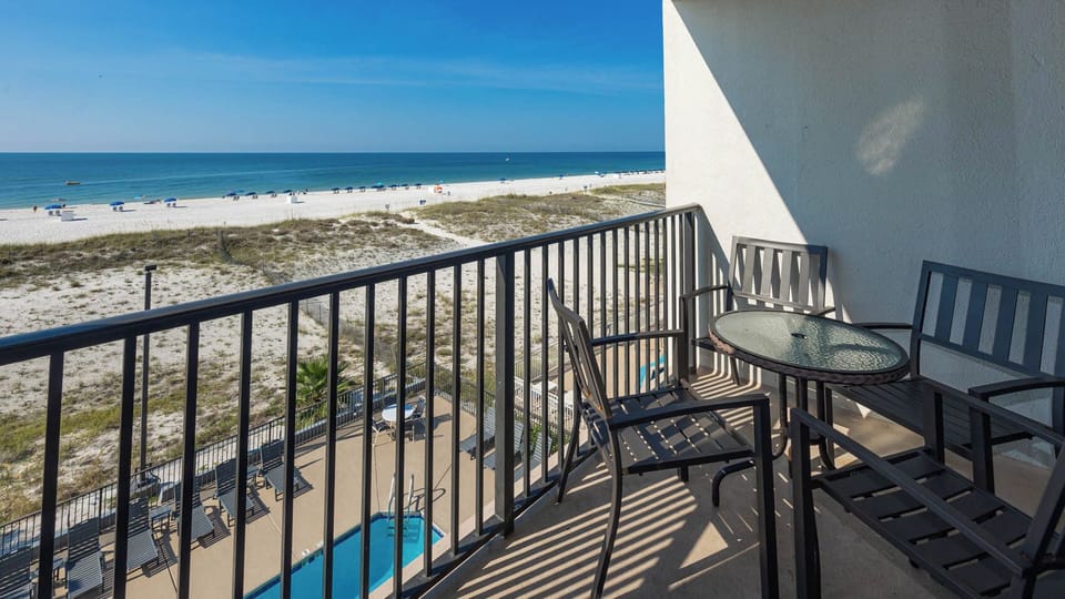 Enjoy a relaxing view from the balcony with seating, overlooking the beachfront and pool area
