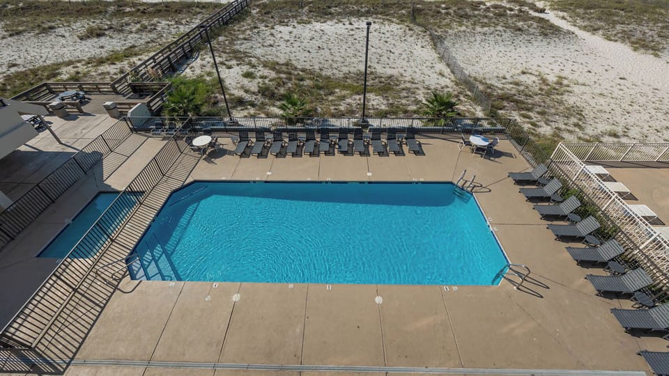 This inviting pool area features a sparkling blue pool surrounded by lounge chairs, perfect for relaxation and fun in the sun