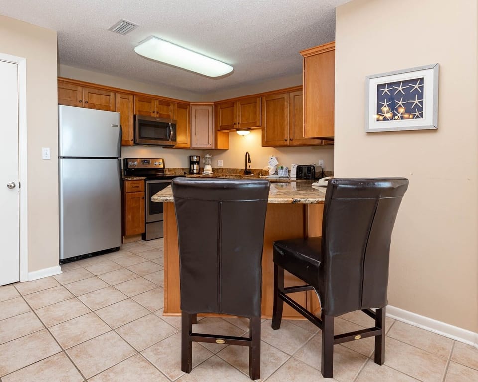 Gather around the granite countertop for meals and drinks in this inviting kitchen with stainless appliances