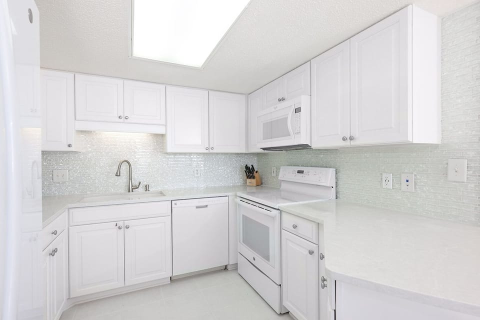 Bright white cabinetry and light countertops create a fresh, inviting space in this modern kitchen with ample storage