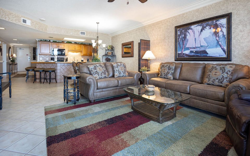 Unwind in the comfortable living area featuring leather sofas, a glass coffee table, and vibrant area rugs