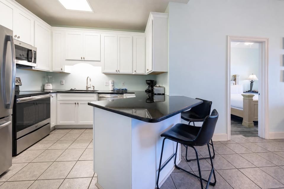 White cabinetry complements the sleek black countertops in this inviting kitchen area with seating at the breakfast bar