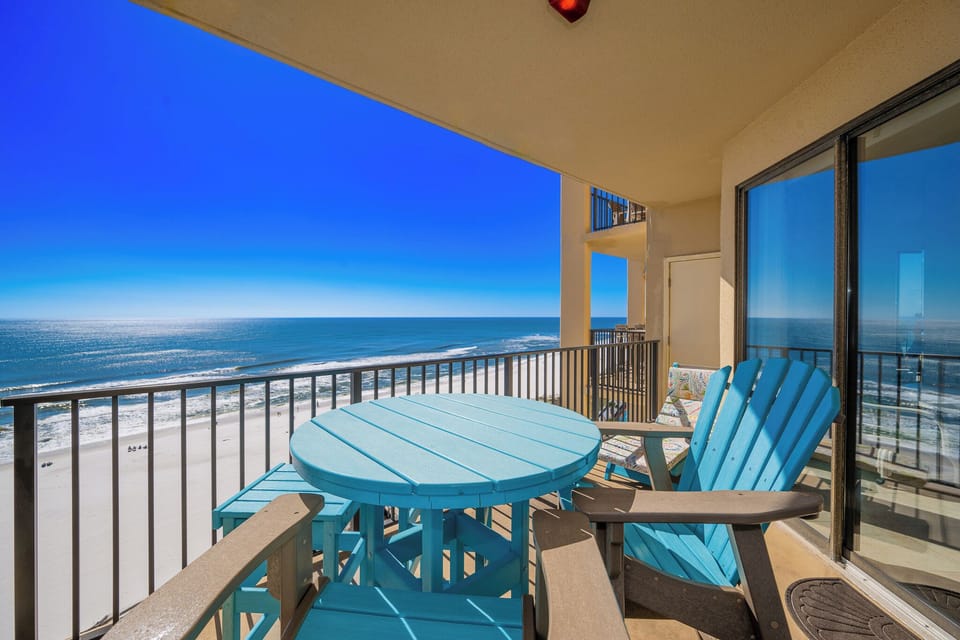 Relax on the vibrant turquoise patio furniture while enjoying sweeping views of the beach and sparkling water