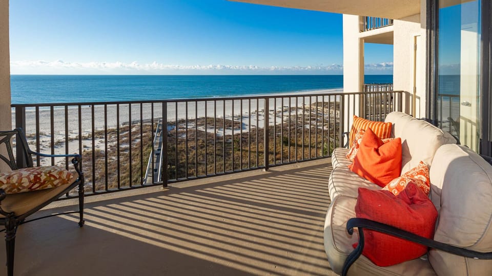 Relax on the comfortable sofa adorned with vibrant pillows, enjoying expansive views of the tranquil waters below