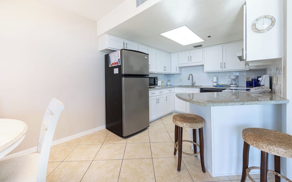 Prepare meals in this stylish kitchen, featuring bar seating and stainless appliances for a pleasant cooking experience