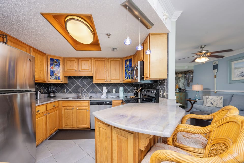 The kitchen features light wood cabinetry, a stylish countertop, and stainless appliances, creating a welcoming cooking space