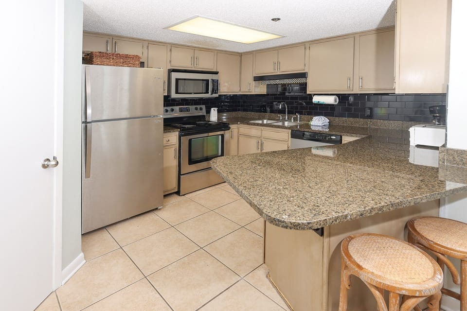 Prepare meals in the spacious kitchen featuring sleek appliances, ample counter space, and a cozy breakfast bar