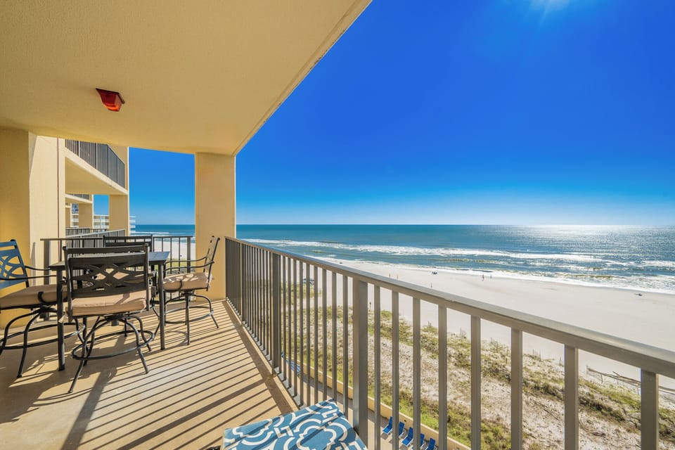 Relax on the balcony with a dining set, enjoying the expansive beach view and vibrant blue skies
