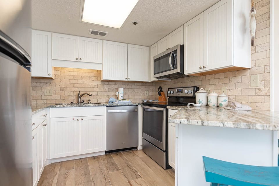 Prepare meals in this inviting kitchen with stylish cabinetry, stainless appliances, and a charming coastal decor