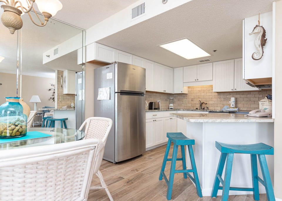 Gather around the glass dining table, enjoying meals with a view of the inviting kitchen and charming decor