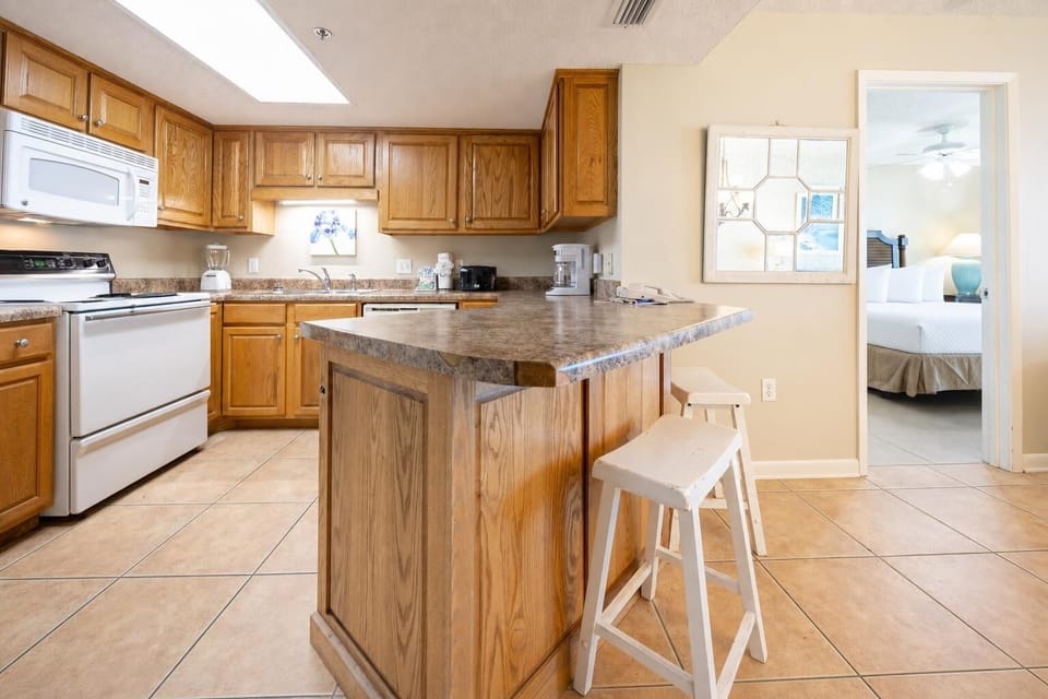 Warm wood cabinetry complements the kitchen's countertop, featuring a breakfast bar with white stools