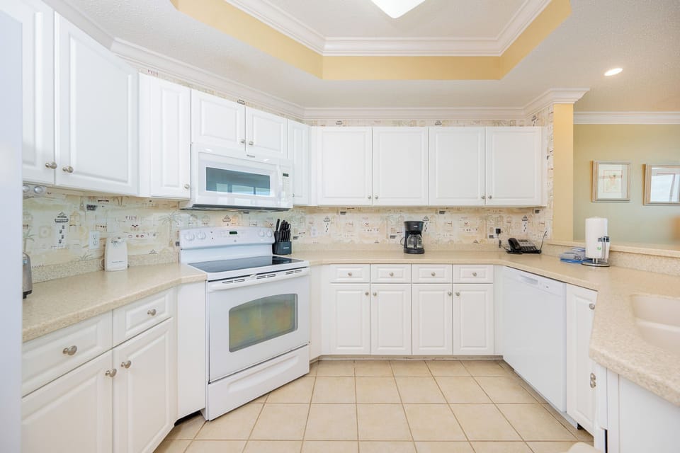 Prepare meals in this kitchen with sleek cabinetry, white appliances, and spacious countertops